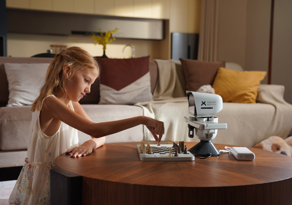 Young girl playing with SenseRobot Chess Mini, an interactive AI chess robot for kids, in a cozy family living room.